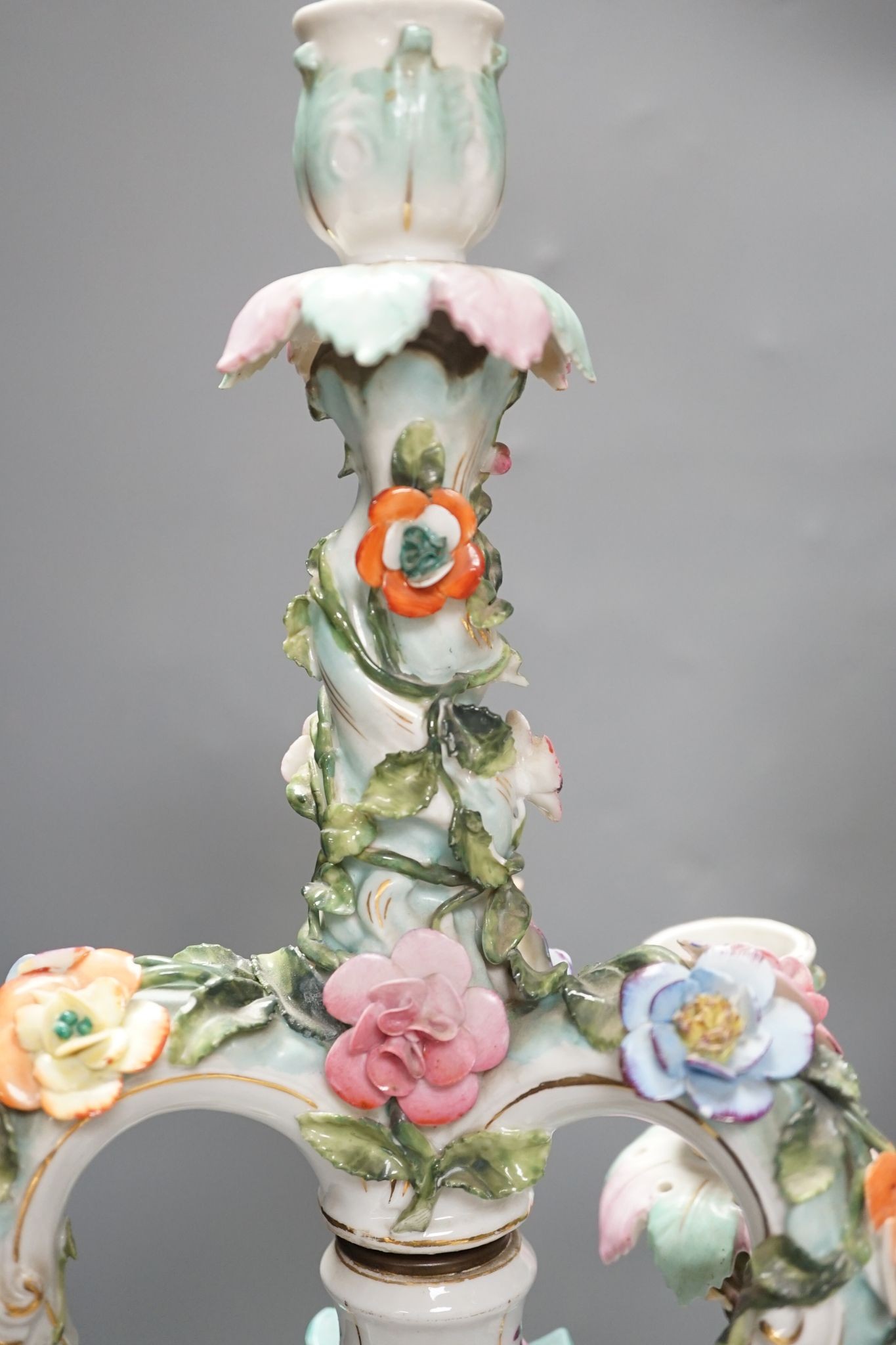 A pair of late 19th century German floral encrusted, figurative porcelain candelabra, 52 cms high.